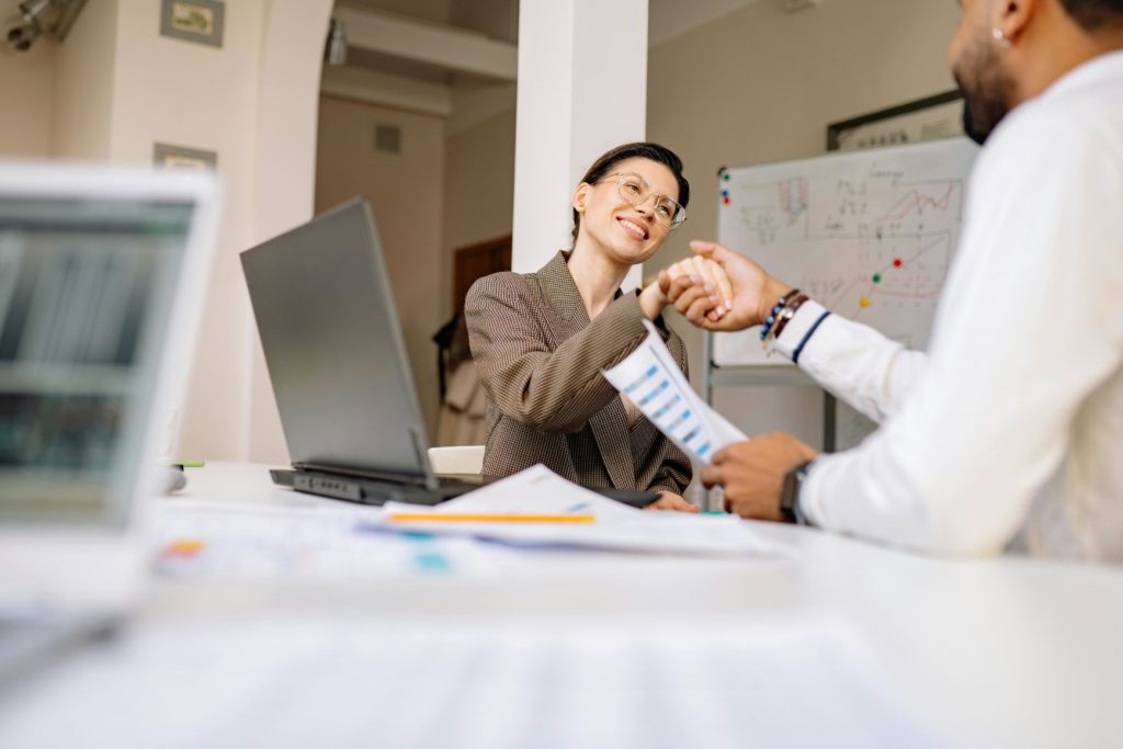 pexels-photo-7691744-7691744 Two professionals smiling and shaking hands in a modern office setting.