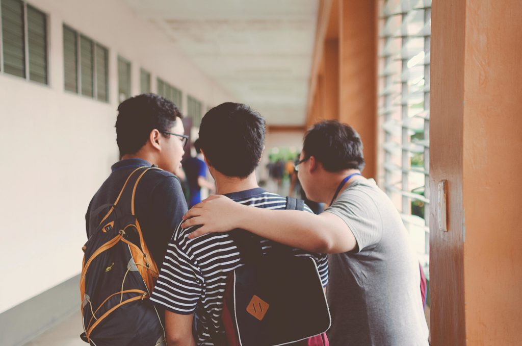 pexels-photo-1516440-1516440 Group of male teenagers walking in a school corridor with backpacks, bonding and chatting.